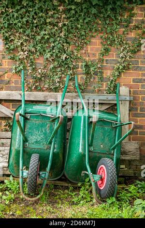 Zwei Schubkarren lehnen sich an einer Gartenwand Stockfoto