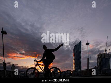 Ein Radfahrer mit Silhouette vor dem Hintergrund des Lots Road Kraftwerks, Chelsea Harbour und Stockfoto