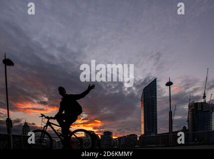 Ein Radfahrer mit Silhouette vor dem Hintergrund des Lots Road Kraftwerks, Chelsea Harbour und Stockfoto