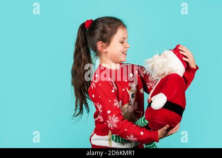 Lieber Weihnachtsmann. Kleines Kind tragen Santa Spielzeug blauen Hintergrund. Kleines Mädchen Spielzeug vorhanden. Winterurlaub. Geschenk bringt Freude und Glück. frohe weihnachten. Weihnachtsstimmung Konzept. Weihnachtstraditionen. Stockfoto