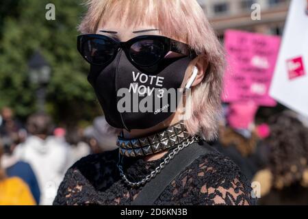 Ein Protestant schaut während der Demonstration mit einer Gesichtsmaske im Washington Square Park an.Tausende gingen zu Frauenmärschen auf die Straßen in den USA, viele trugen pinkfarbene Protesthüte, während sie inbrünstige Rufe gegen Präsident Donald Trump und seinen konservativen Obersten Gerichtshof ausstellten. Die Kundgebungen vor den Wahlen am 3. November wurden vom ersten Frauenmarsch in Washington DC inspiriert, einer riesigen Anti-Trump-Kundgebung, die einen Tag nach seiner Amtseinführung im Jahr 2017 stattfand. Stockfoto