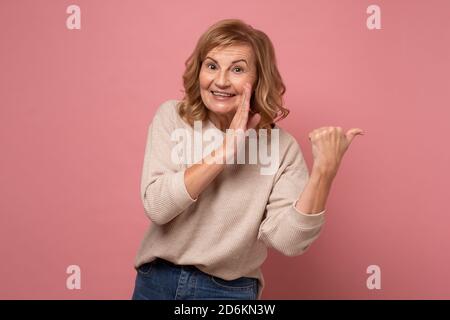 Schöne Frau mittleren Alters hält Hand auf Mund erzählen Geheimnis Gerücht Stockfoto