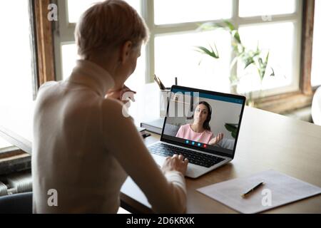 Rückansicht Geschäftsfrau macht Videoanruf, verhandelt mit diversen Kollegen Stockfoto