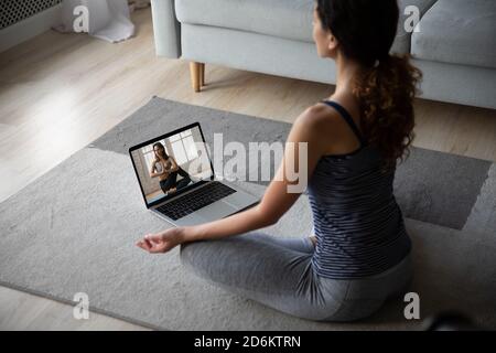 Rückansicht junge Frau trägt Sportkleidung Yoga üben, mit Laptop Stockfoto