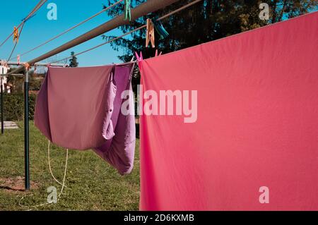 Rosafarbene und violette Bettlaken hängen an einem Trockengestell im Garten (Pesaro, Italien, Europa) Stockfoto