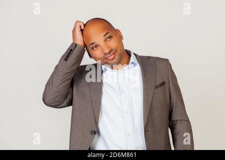 Junger Mann afroamerikanischen Geschäftsmann hält seine Hand auf der Stirn mit einem schuldigen Ausdruck. Verwirrt stehen auf grauem Hintergrund Stockfoto