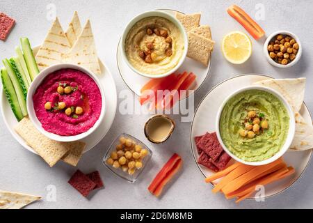 Verschiedene Hummus Dips in Schüsseln, serviert mit frischem Gemüse und Chips. Stockfoto
