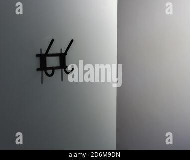 Minimalistisches Foto, eine weiße Wand mit einem Kleiderbügel Stockfoto
