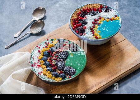 Grüne und blaue Spirulina Smoothie Schalen mit Obst und Leinsamen - gesunde Superfood Frühstücksidee. Weitwinkelansicht Stockfoto