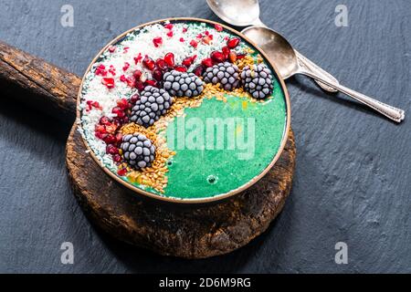Grüne Spirulina Smoothie Schale mit Obst und Leinsamen - gesunde Superfood Frühstücksidee. Stockfoto