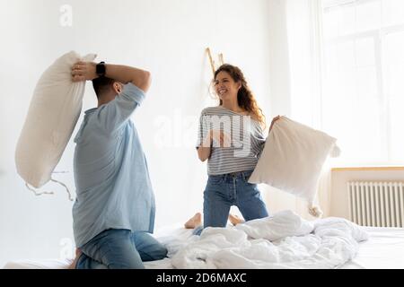 Glücklich lachend junges Paar spielen Kissen Kampf im Schlafzimmer Stockfoto