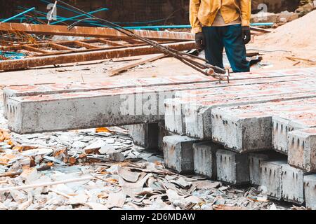 Pile Betonsäulen auf dem Boden Arbeiter bewegen sich durch Schlinge Auf der Baustelle Stockfoto