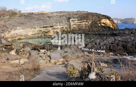 Oberer Teil von Angel's Billabong mit Schild mit oberem Pool, erodiertem schwarzen Felsen, Klippe und Meer im Hintergrund in Nusa Penida, Indonesien Stockfoto