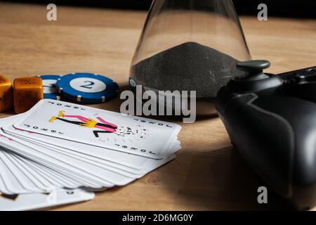 Spiele Nacht Aufenthalt mit Freunden Hintergrund Poker Chips Würfel & Karten Videospiele Controller auf Holztisch. Bleiben in Freunden Aktivität Spiele. Stockfoto