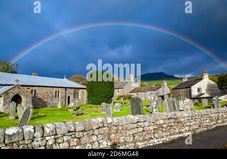 Regenbogen über der Dorfkirche St. Oswalds in der Yorkshire Dorf Horton in Ribblesdale mit dem Berg von Pen-y-ghent auf dem Pennine Way Stockfoto