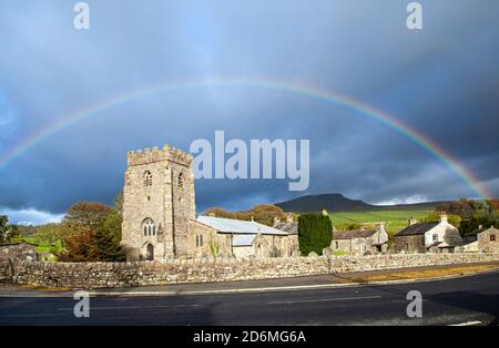 Regenbogen über der Dorfkirche St. Oswalds in der Yorkshire Dorf Horton in Ribblesdale mit dem Berg von Pen-y-ghent auf dem Pennine Way Stockfoto