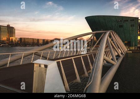 Moderne Brücke über den Oosterdok-Kanal, der zur Nemo Science führt Museum in Amsterdam Stockfoto