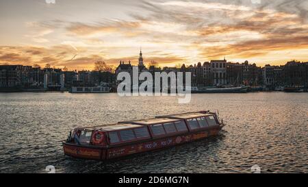 Amsterdam, Niederlande, 6. Januar 2020: Tour Boot Segeln auf dem Oosterdok Kanal mit im Hintergrund die charakteristischen Kanalhäuser und festgemacht sh Stockfoto