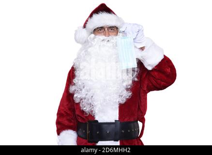 Älterer Mann trägt ein traditionelles Sant Claus Kostüm mit einer chirurgischen Maske, die jeden daran erinnert, sich während der Covid-19 Pandemie zu maskieren. Stockfoto