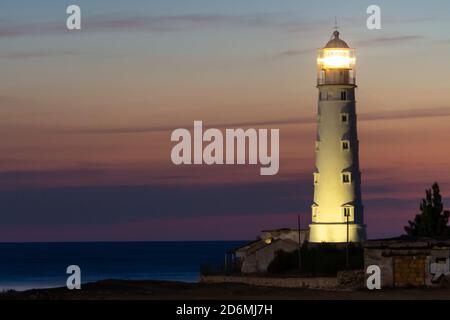 Ein Leuchtturm am Meer leuchtete in der Dämmerung Stockfoto