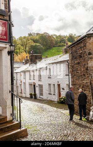 Person, die durch die gepflasterten Straßen des Dorfes Cumbrian aufwacht Von Dent in Dentdale im Yorkshire Dales Nationalpark Cumbria England Großbritannien Stockfoto