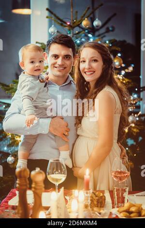 Familie mit Kleinkind und schwangere Frau feiern Weihnachten Stockfoto