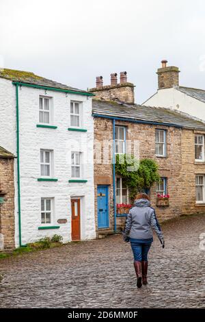 Person, die durch die gepflasterten Straßen des Dorfes Cumbrian aufwacht Von Dent in Dentdale im Yorkshire Dales Nationalpark Cumbria England Großbritannien Stockfoto