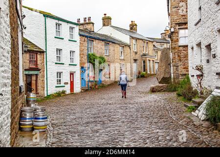 Person, die durch die gepflasterten Straßen des Dorfes Cumbrian aufwacht Von Dent in Dentdale im Yorkshire Dales Nationalpark Cumbria England Großbritannien Stockfoto