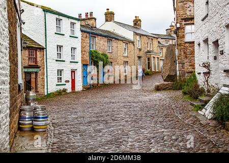 Person, die durch die gepflasterten Straßen des Dorfes Cumbrian aufwacht Von Dent in Dentdale im Yorkshire Dales Nationalpark Cumbria England Großbritannien Stockfoto