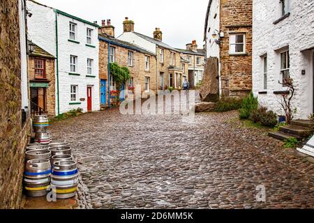 Person, die durch die gepflasterten Straßen des Dorfes Cumbrian aufwacht Von Dent in Dentdale im Yorkshire Dales Nationalpark Cumbria England Großbritannien Stockfoto