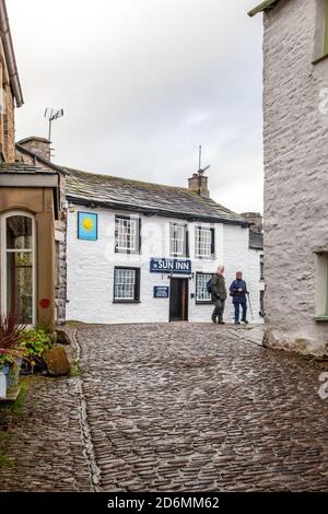 Person, die durch die gepflasterten Straßen des Dorfes Cumbrian aufwacht Von Dent in Dentdale im Yorkshire Dales Nationalpark Cumbria England Großbritannien Stockfoto