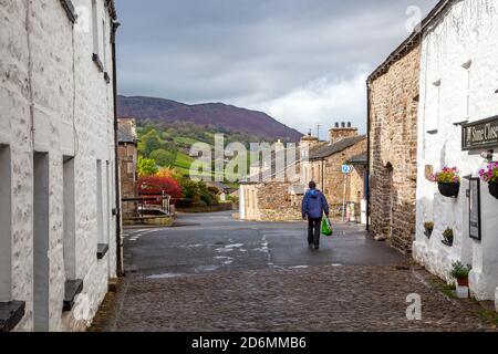 Person, die durch die gepflasterten Straßen des Dorfes Cumbrian aufwacht Von Dent in Dentdale im Yorkshire Dales Nationalpark Cumbria England Großbritannien Stockfoto