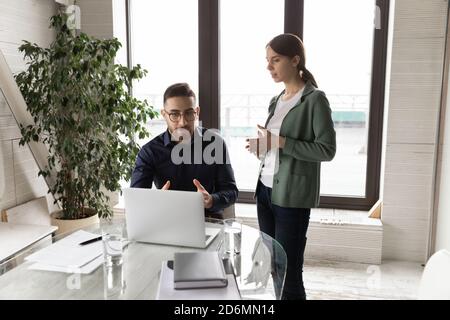 Junge Praktikantin teilt erste Projektergebnisse mit dem Chef. Stockfoto
