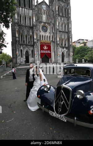 Pre-Wedding Pose eines jungen vietnamesischen Paares mit einem klassischen Citroen Traction Avant Auto vor der St. Joseph's Cathedral in Hanoi, Vietnam. Stockfoto