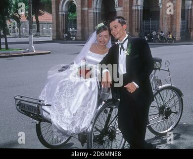 Ein vietnamesisches Paar posiert für Vorhochzeit-Fotos mit einer Rikscha vor der Kathedrale Notre Dame de Saigon, Ho Chi Minh City, Vietnam Stockfoto