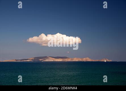 Cumulus Wolke schwebt über der Insel Dia, nördlich von Kreta an einem Tag mit klarem Himmel, Segelboot und andere Boote im Horizont sichtbar. Stockfoto