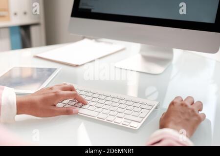 Hände einer jungen modernen Geschäftsfrau, die die Finger auf den Tasten der Tastatur hält Stockfoto