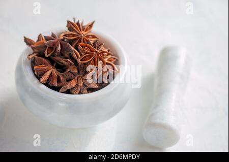 Sternanis in einem Mörser und Stößel ist bereit, zerkleinert werden. Würzen. Nahaufnahme. Speicherplatz kopieren Stockfoto