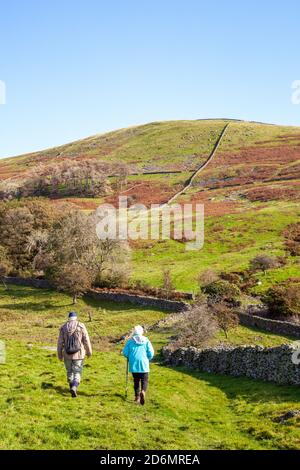 Ältere Mann und Frau Paar Rentner Senioren zu Fuß wandern Backpacking im Norden Yorkshire Dales in den Hügeln darüber Kirkby Lonsdale Stockfoto