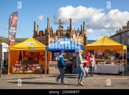 Leute, die an Marktständen auf dem Marktplatz vorbeilaufen Die Cumbrian Stadt Kirkby Lonsdale England Stockfoto