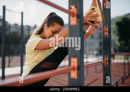Starke junge Frau streckt die Beine in der Nähe der Wand bar Stockfoto