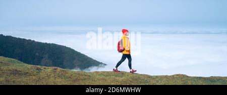 Junge Backpacker-Frau gekleidet orange wasserdichte Jacke Wandern am Berg über der Wolke Route Ende Februar auf Madeira Insel Portug Stockfoto