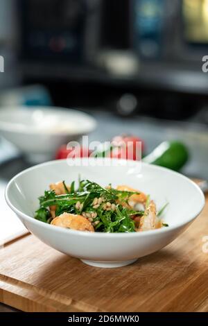 Holzbrett mit weißen Keramikschale mit appetitlichen Salat für Gast Stockfoto