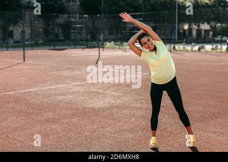 Lächelnde Frau in Sportkleidung Vorbereitung für das Training im Freien Stockfoto