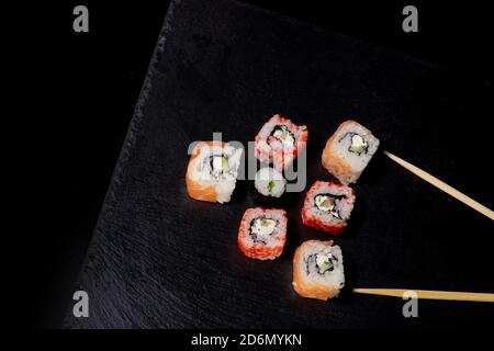 Philadelphia Rolle mit Lachs, Käse und Gurke auf schwarzem Hintergrund. Sushi Philadelphia Stockfoto