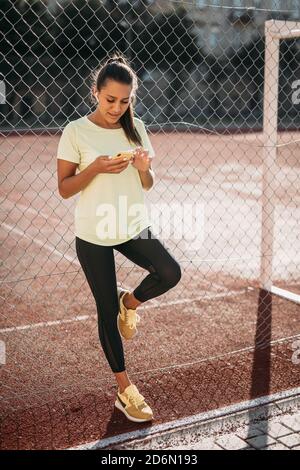 Schöne Frau mit Smartphone beim Entspannen im Stadion Stockfoto