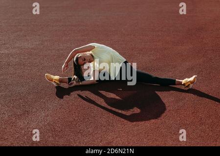Junge Brünette Biegen Körper auf Sportplatz Stockfoto