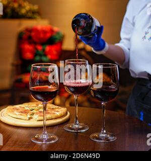 Nahaufnahme des Kellners, der Wein in Gläser im Restaurant gießt. Buffet-Tisch Feier der Weinprobe. Stockfoto
