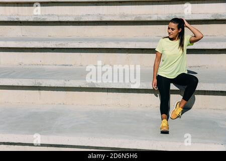 Fitness Frau sitzt auf der Treppe und Sonnenstrahlen genießen. Stockfoto