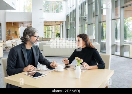 Zwei selbstbewusste Kollegen diskutieren bei einem Meeting im Restaurant über Finanznachrichten Stockfoto